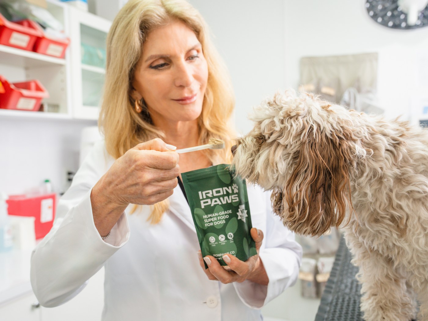 Dr. Sharon MacIvor, DVM, feeding a dog a scoop of Iron Paws in her clinic