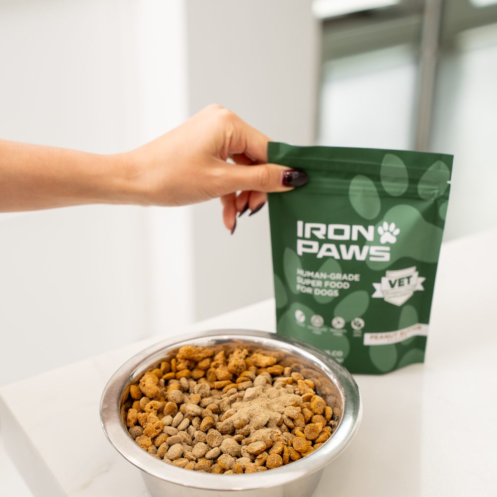 Iron Paws powder sprinkled over a bowl of kibble